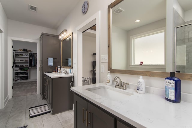 bathroom featuring tile patterned flooring, visible vents, a spacious closet, and a tile shower