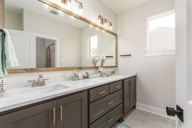 bathroom with baseboards, visible vents, a sink, and double vanity