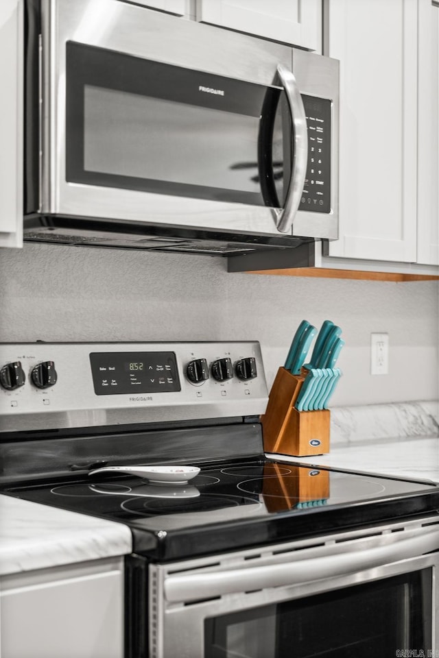 room details with white cabinets, light stone countertops, and appliances with stainless steel finishes
