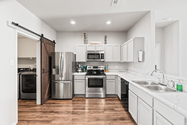 kitchen with stainless steel appliances, wood finished floors, visible vents, and a sink