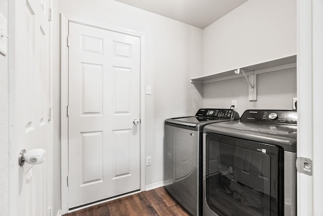 clothes washing area with dark wood finished floors, washing machine and clothes dryer, baseboards, and laundry area