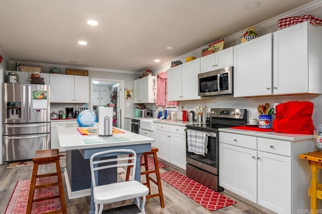 kitchen with light countertops, crown molding, appliances with stainless steel finishes, and light wood finished floors