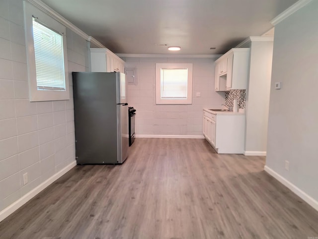 kitchen with white cabinets, light countertops, wood finished floors, freestanding refrigerator, and crown molding