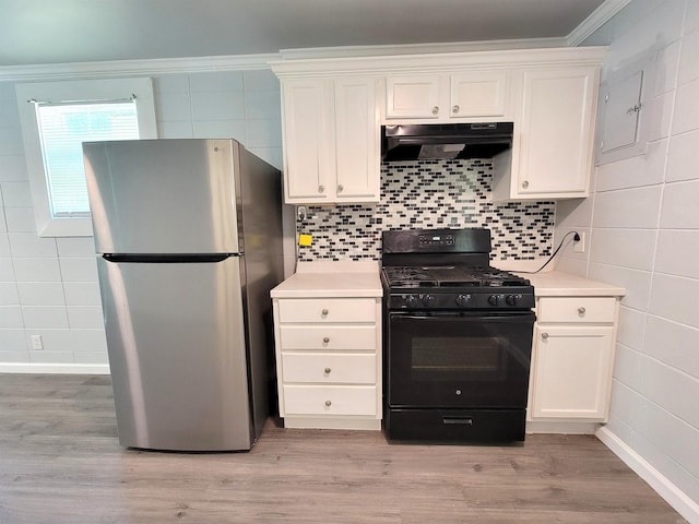 kitchen featuring white cabinets, black range with gas stovetop, freestanding refrigerator, and under cabinet range hood