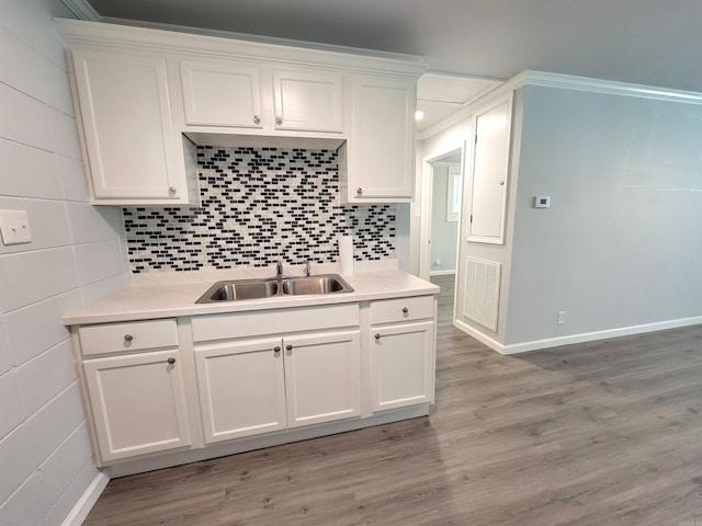 kitchen with white cabinets, a sink, baseboards, visible vents, and light countertops