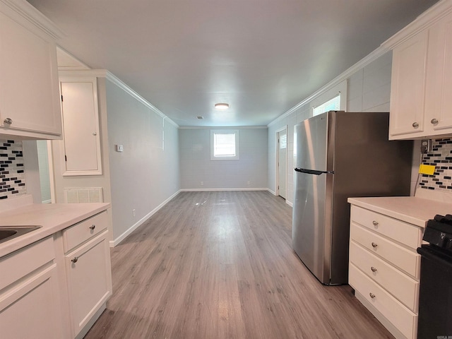 kitchen featuring stove, light countertops, crown molding, and white cabinetry