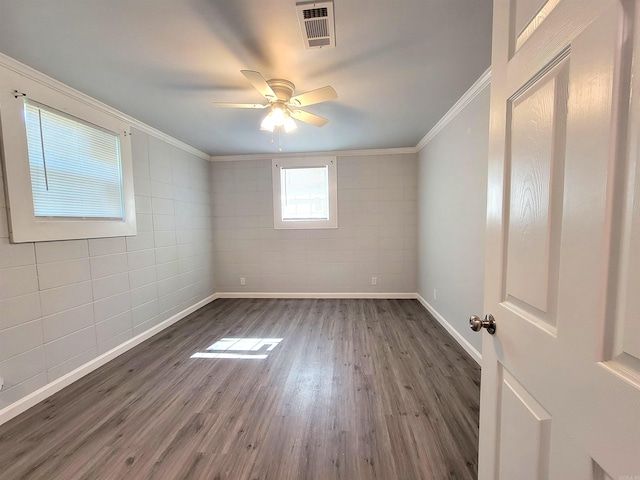 spare room featuring ceiling fan, ornamental molding, wood finished floors, and visible vents