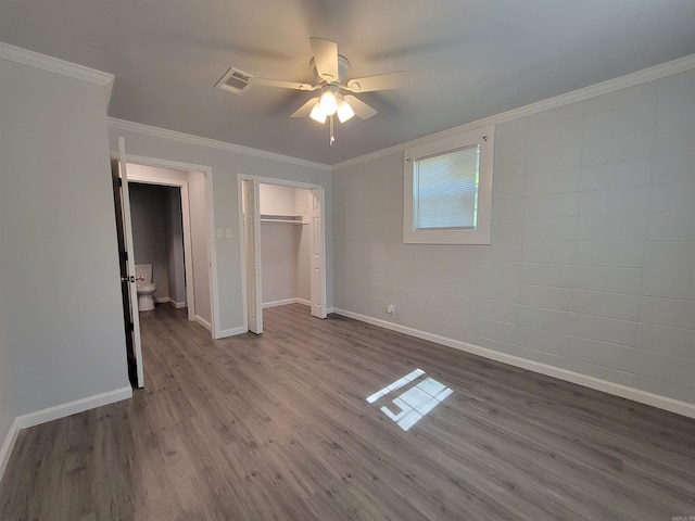 unfurnished bedroom featuring crown molding, a closet, baseboards, dark wood-style flooring, and visible vents