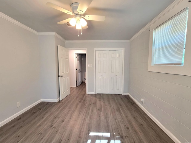 unfurnished bedroom with wood finished floors, baseboards, a closet, and crown molding