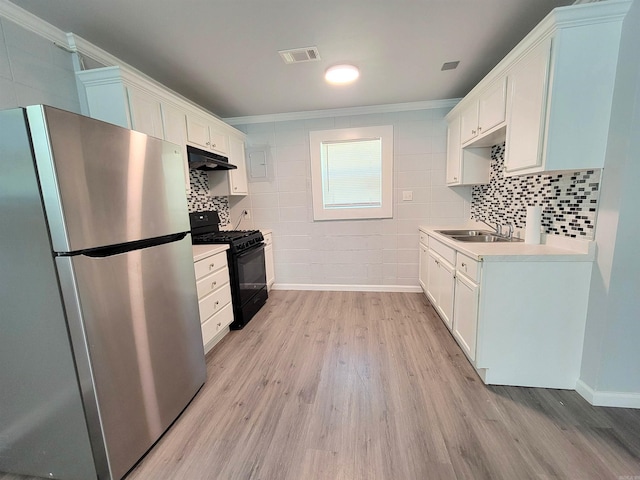 kitchen with black range with gas stovetop, a sink, under cabinet range hood, visible vents, and freestanding refrigerator