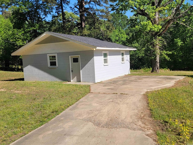 view of front of home featuring a front lawn, concrete block siding, and an outbuilding