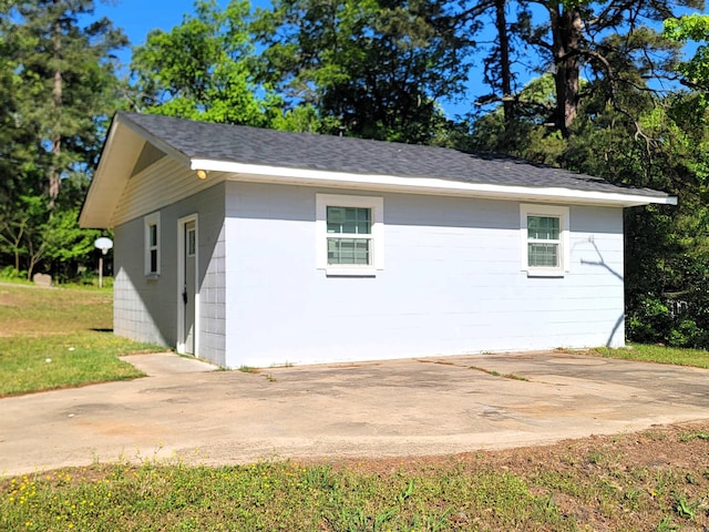 view of side of property featuring roof with shingles and concrete block siding