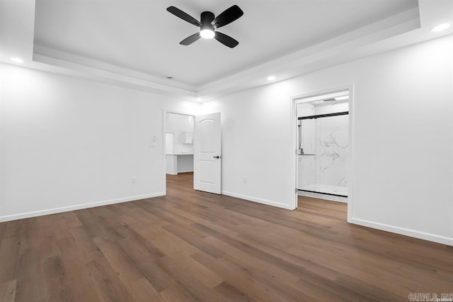 unfurnished bedroom featuring baseboards, wood finished floors, recessed lighting, and a raised ceiling