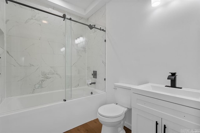 bathroom featuring wood finished floors, combined bath / shower with glass door, toilet, and vanity