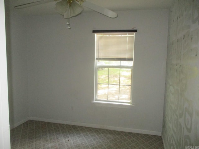 carpeted empty room featuring baseboards and a ceiling fan