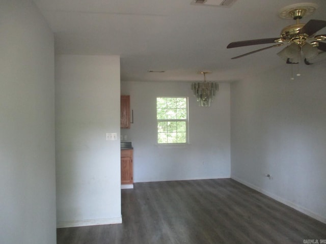 unfurnished room featuring ceiling fan with notable chandelier, baseboards, visible vents, and dark wood finished floors
