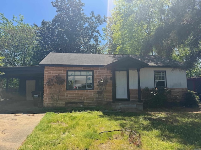 ranch-style home featuring a front lawn, roof with shingles, concrete driveway, an attached carport, and brick siding