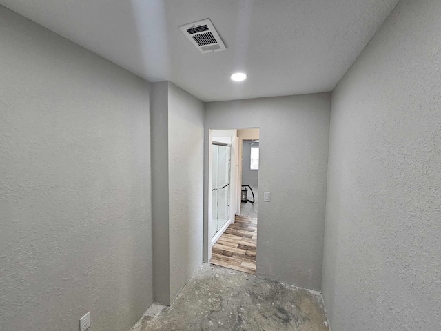 corridor featuring a textured wall and visible vents