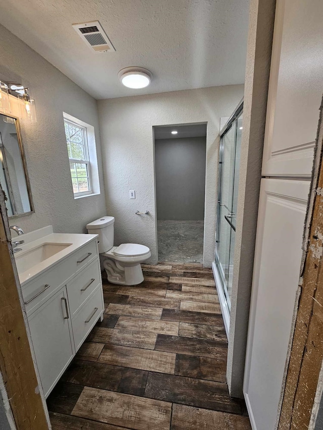 full bath featuring a textured ceiling, a stall shower, visible vents, wood finished floors, and a textured wall