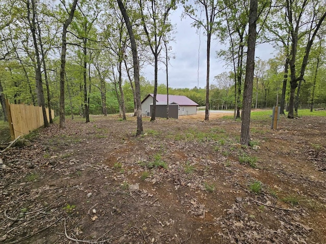 view of yard with a wooded view and fence