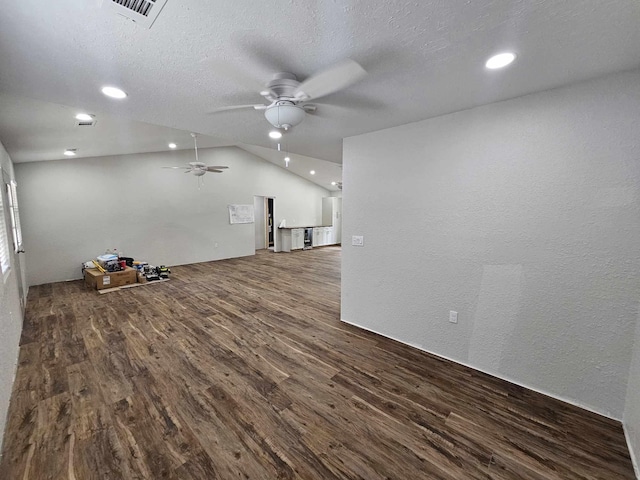 empty room with visible vents, lofted ceiling, a ceiling fan, wood finished floors, and a textured wall
