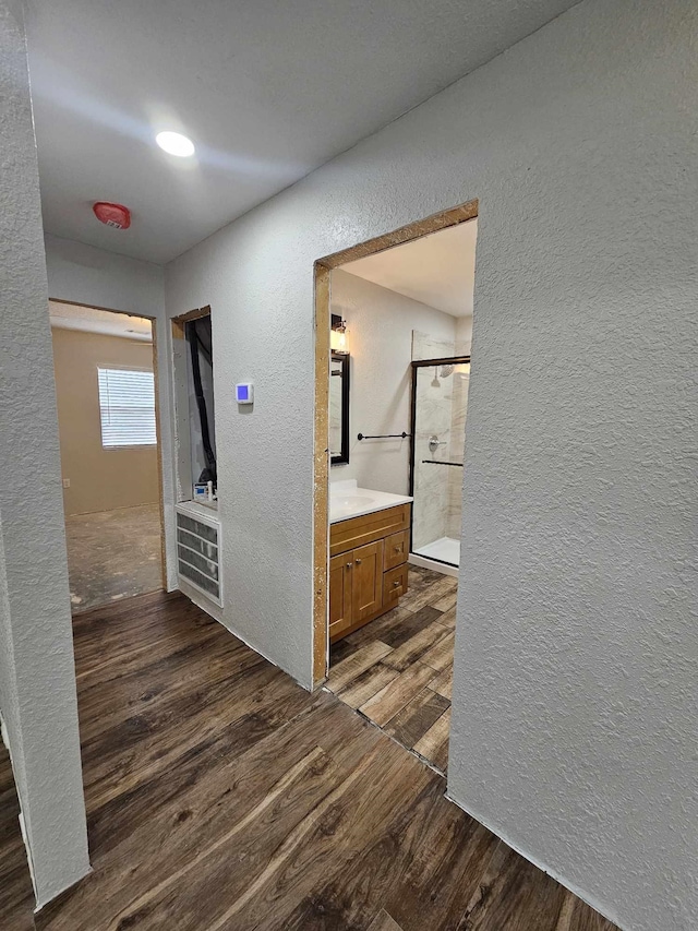 hallway with dark wood-style flooring and a textured wall
