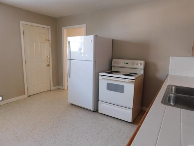 kitchen with tile counters, a sink, and white appliances