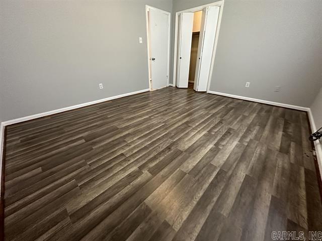 unfurnished bedroom featuring baseboards and dark wood-type flooring