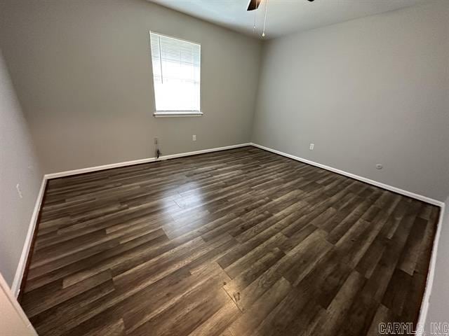 spare room featuring dark wood-type flooring, baseboards, and ceiling fan