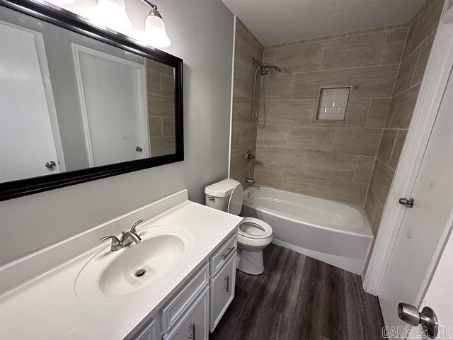 bathroom featuring toilet, vanity, wood finished floors, and bathing tub / shower combination