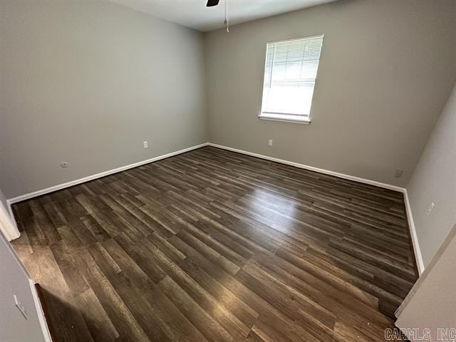 spare room featuring dark wood finished floors, a ceiling fan, and baseboards
