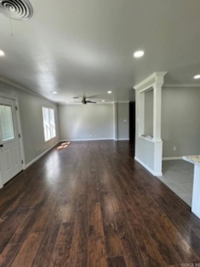 unfurnished living room featuring crown molding, visible vents, a ceiling fan, and dark wood-style floors