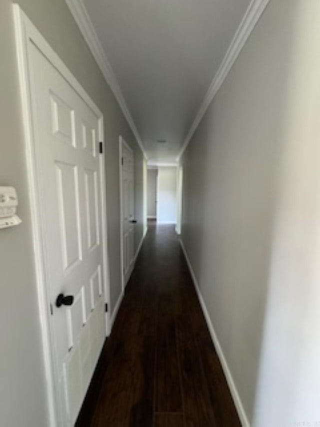 hallway with dark wood finished floors, baseboards, and ornamental molding