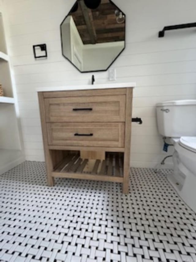 bathroom with wooden walls, vanity, and toilet