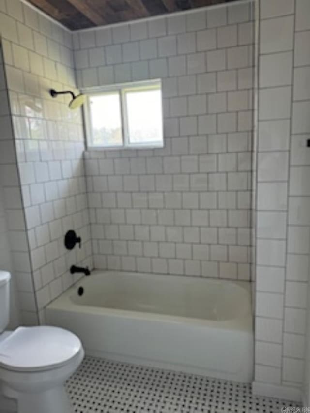 bathroom featuring washtub / shower combination, tile patterned flooring, and toilet