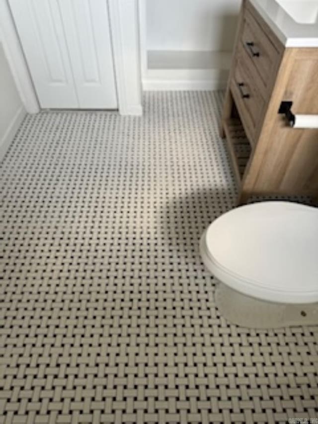 bathroom with baseboards, vanity, and toilet
