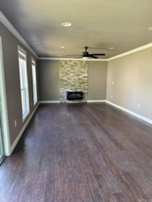 unfurnished living room featuring dark wood finished floors, ceiling fan, baseboards, and crown molding