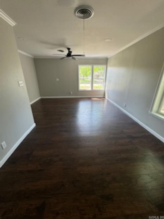 spare room with a ceiling fan, baseboards, dark wood-type flooring, and crown molding