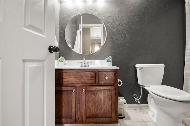bathroom with toilet, baseboards, tile patterned flooring, a textured wall, and vanity