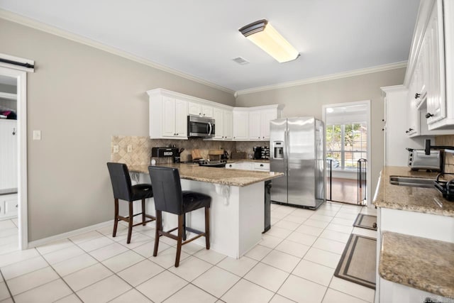 kitchen featuring a peninsula, crown molding, decorative backsplash, white cabinets, and appliances with stainless steel finishes