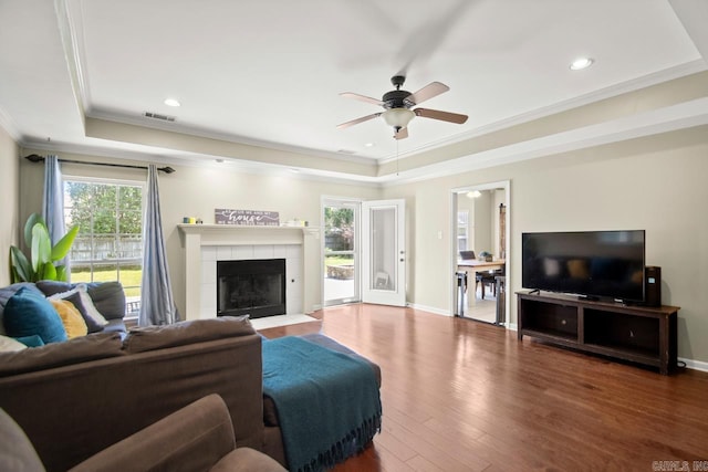 living area with ornamental molding, a raised ceiling, a ceiling fan, and visible vents
