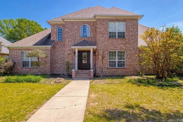 traditional-style home featuring brick siding, roof with shingles, and a front yard