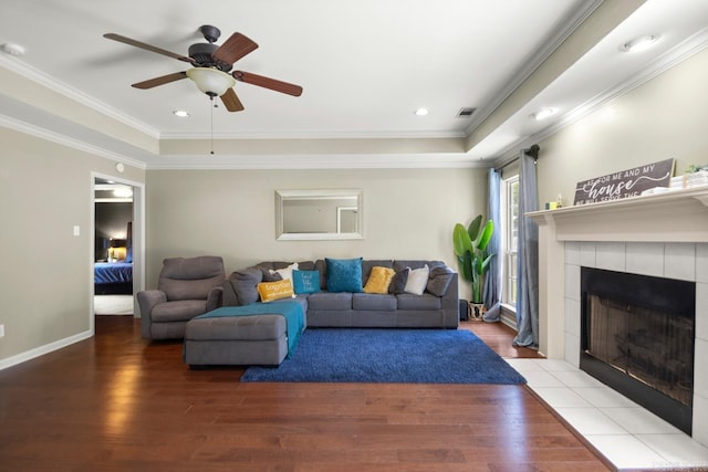 living area featuring crown molding, ceiling fan, a tile fireplace, and wood finished floors