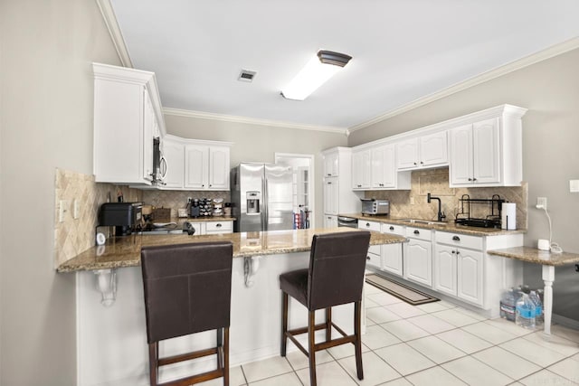 kitchen featuring visible vents, a sink, a peninsula, backsplash, and appliances with stainless steel finishes