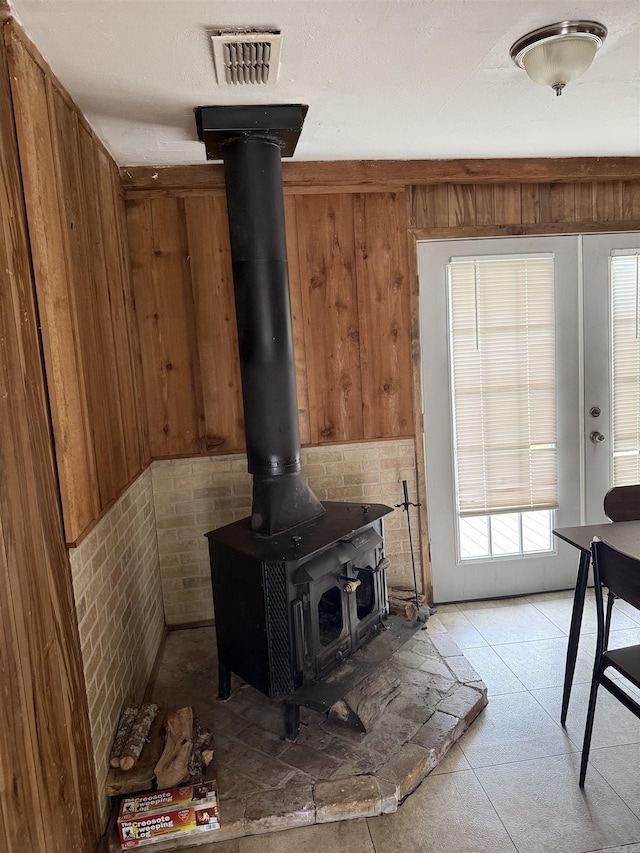 interior space featuring wood walls, a wood stove, and visible vents
