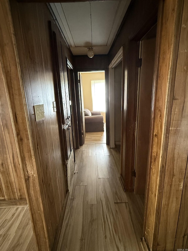 hallway featuring wood walls, attic access, and wood finished floors