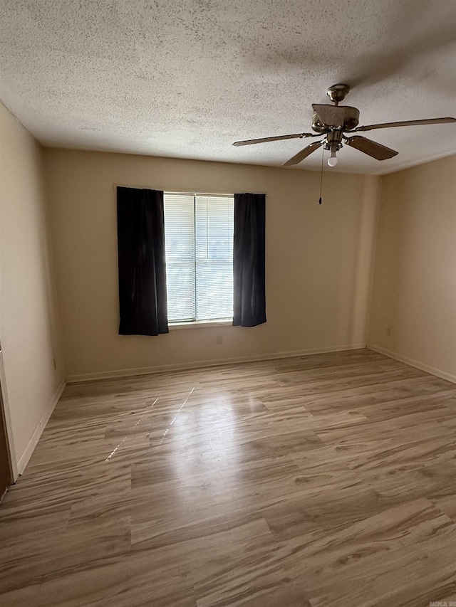 unfurnished room featuring wood finished floors, a textured ceiling, baseboards, and ceiling fan