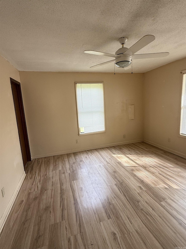 unfurnished room featuring ceiling fan, baseboards, wood finished floors, and a textured ceiling