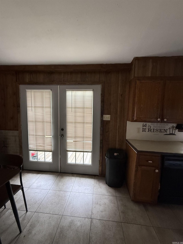 doorway with french doors, wooden walls, and light tile patterned flooring