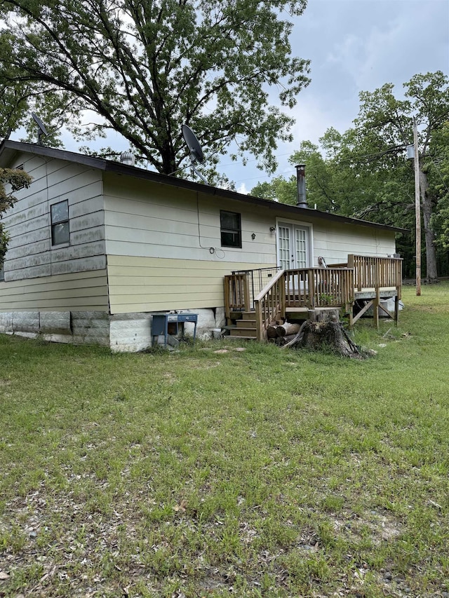 rear view of property with a yard, a deck, and french doors